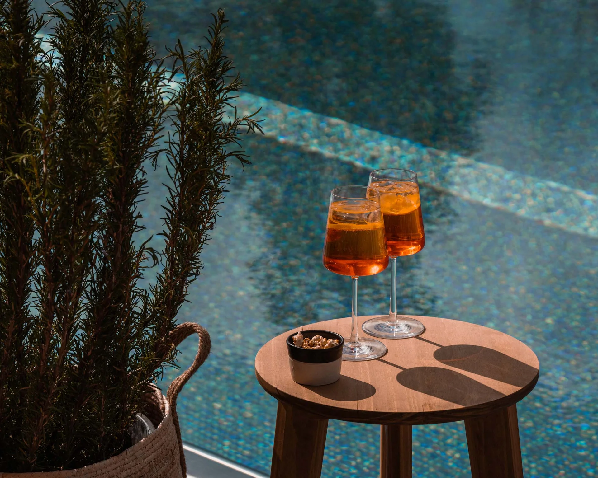 NILS am See: Impressionen eines Orts für das süße Leben Zwei Aperol Spritz-Gläser und Snack auf Holztisch neben Pool