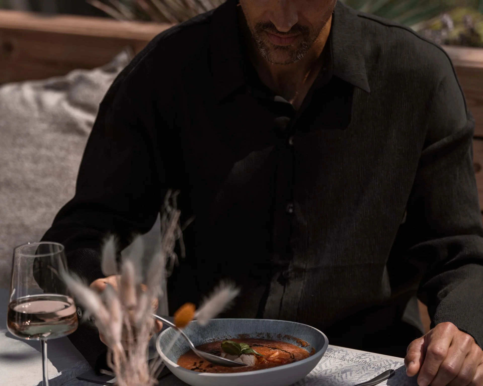 NILS am See: Impressionen eines Orts für das süße Leben Mann sitzt draußen bei Tageslicht und isst Suppe mit Weinglas auf dem Tisch