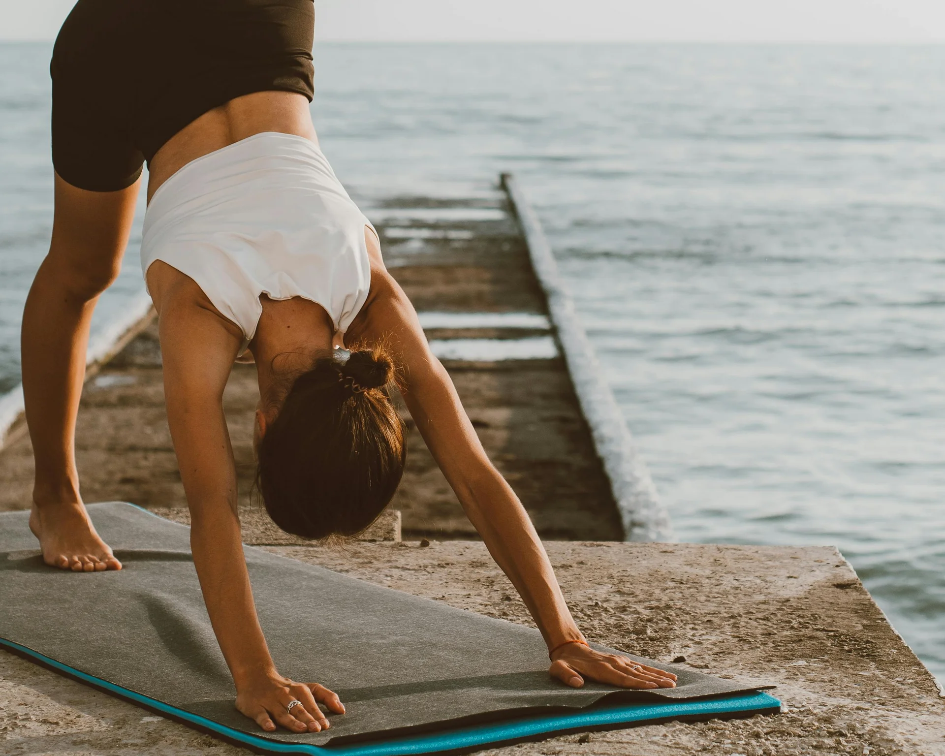 NILS am See: Impressionen eines Orts für das süße Leben Frau macht Yoga mit einem Bein auf einem Steg am Meer