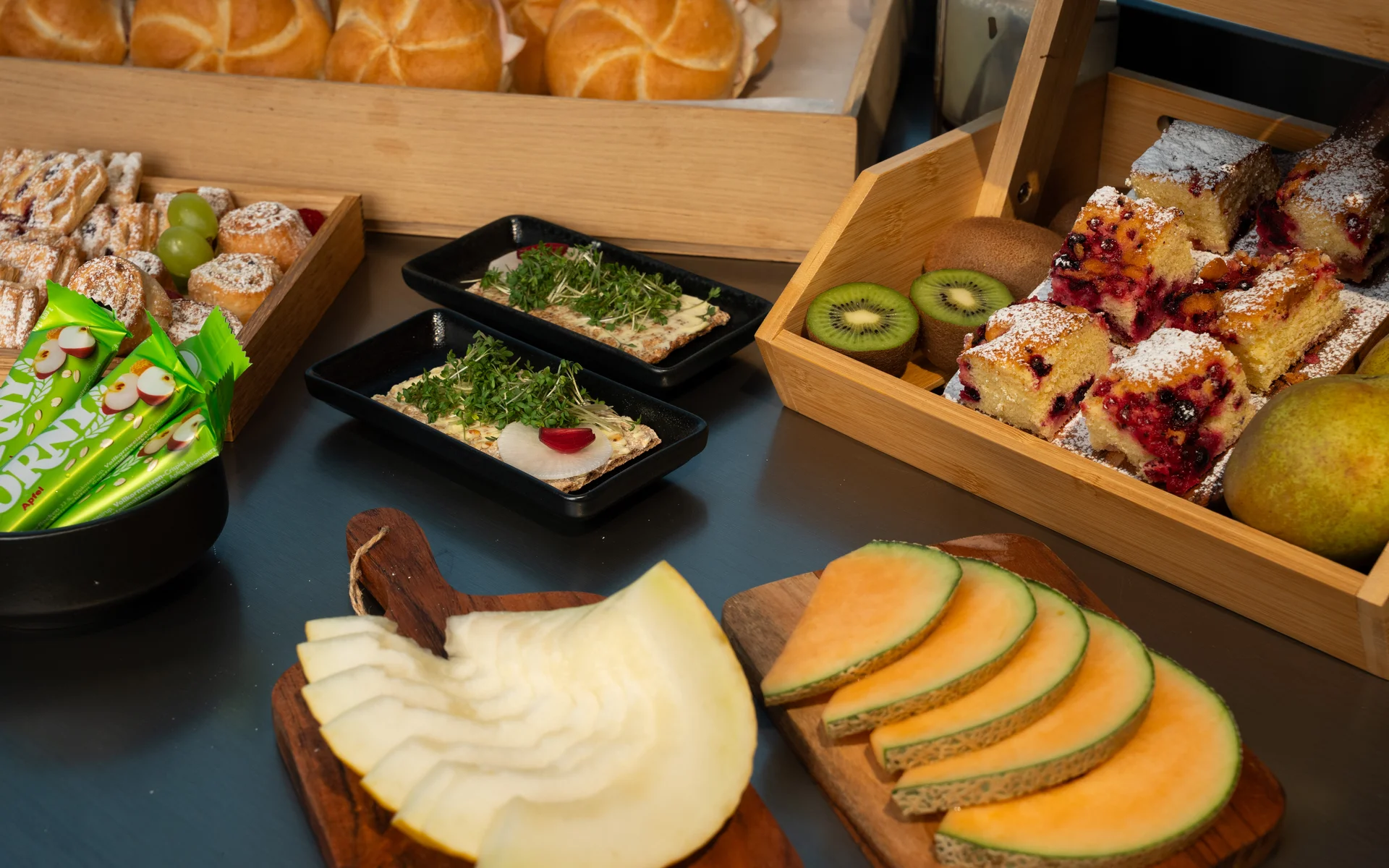 NILS am See: unser Event- und Seminarhotel im Burgenland Verschiedene Brote, Kuchenstücke, frisches Obst und Snacks auf Holzbrettern