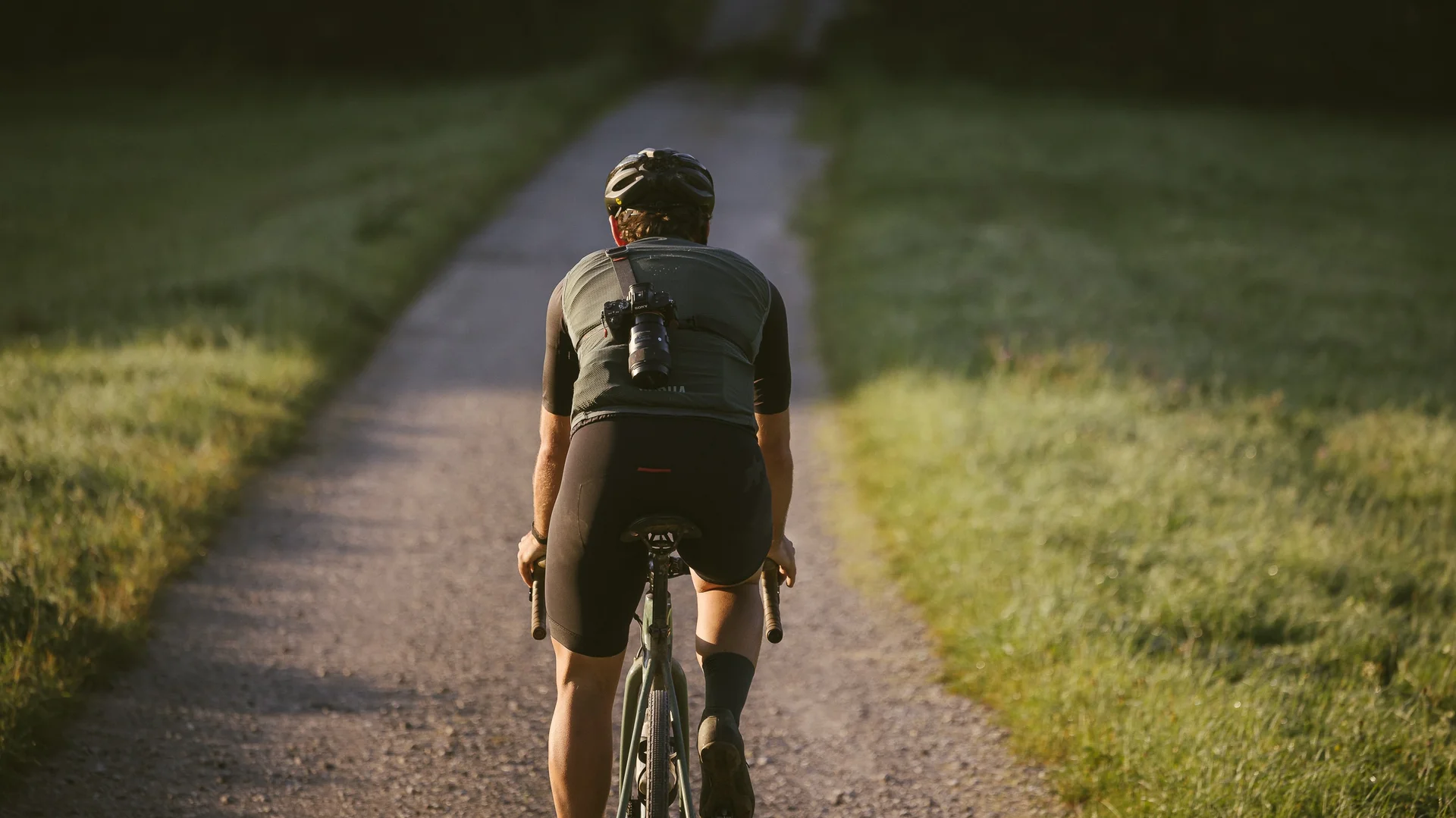 Biken auf dem Neusiedler See Radweg mit Übernachtung im NILS Fahrradfahrer auf schmalem Weg umgeben von Wiese bei Sonnenlicht