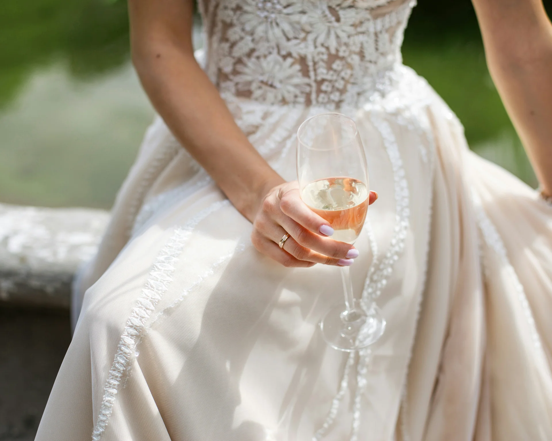 NILS am See: Impressionen eines Orts für das süße Leben Frau im Hochzeitskleid mit Sektglas in der Hand sitzend