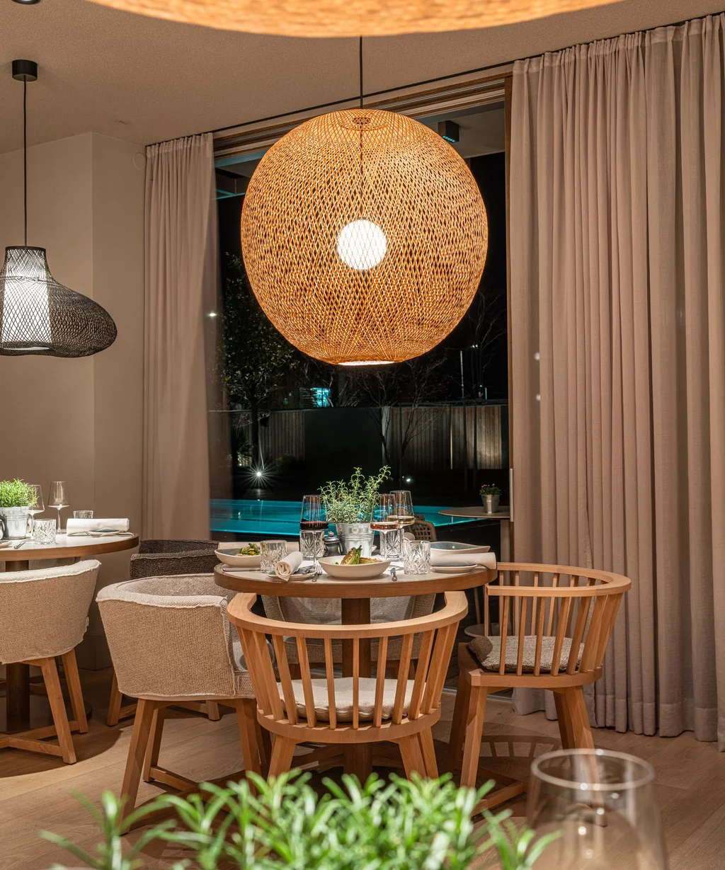 NILS am See Genussmomente: Frühstück nahe Neusiedl am See Gemütlicher Essbereich mit Holzstühlen und warm beleuchteter Deckenlampe
