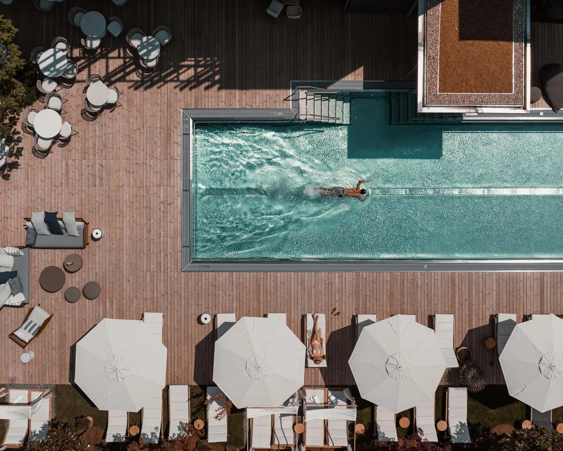 NILS am See: Impressionen eines Orts für das süße Leben Vogelperspektive eines Schwimmers im Pool mit Liegestühlen und Sonnenschirmen