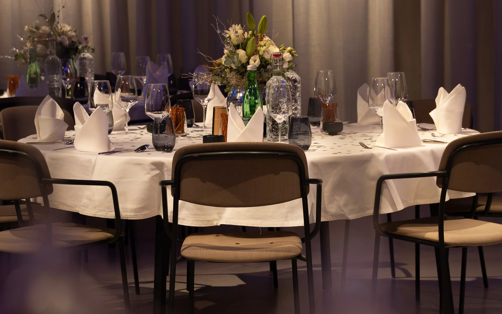 NILS am See: unser Event- und Seminarhotel im Burgenland Eleganter gedeckter Tisch mit Blumenarrangement und Weingläsern in gedämpftem Licht