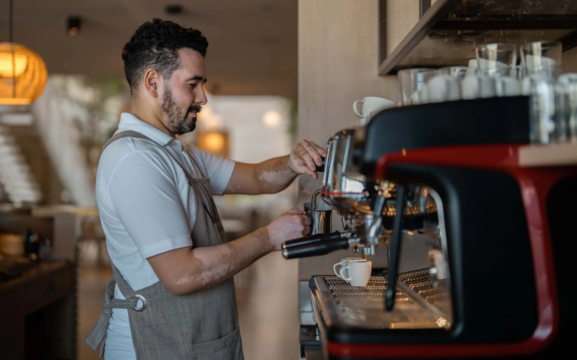 NILS am See: Philosophie und Gastgeber Barista bereitet Kaffee mit Espressomaschine in einem Café zu