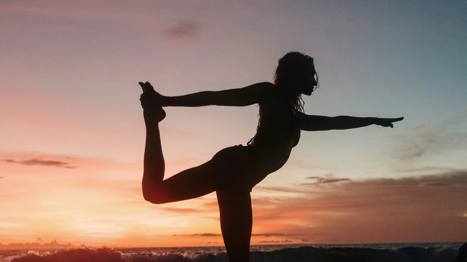 NILS am See: unser Hotel mit Yoga in Österreich Silhouette einer Person, die bei Sonnenuntergang Yoga am Meer macht