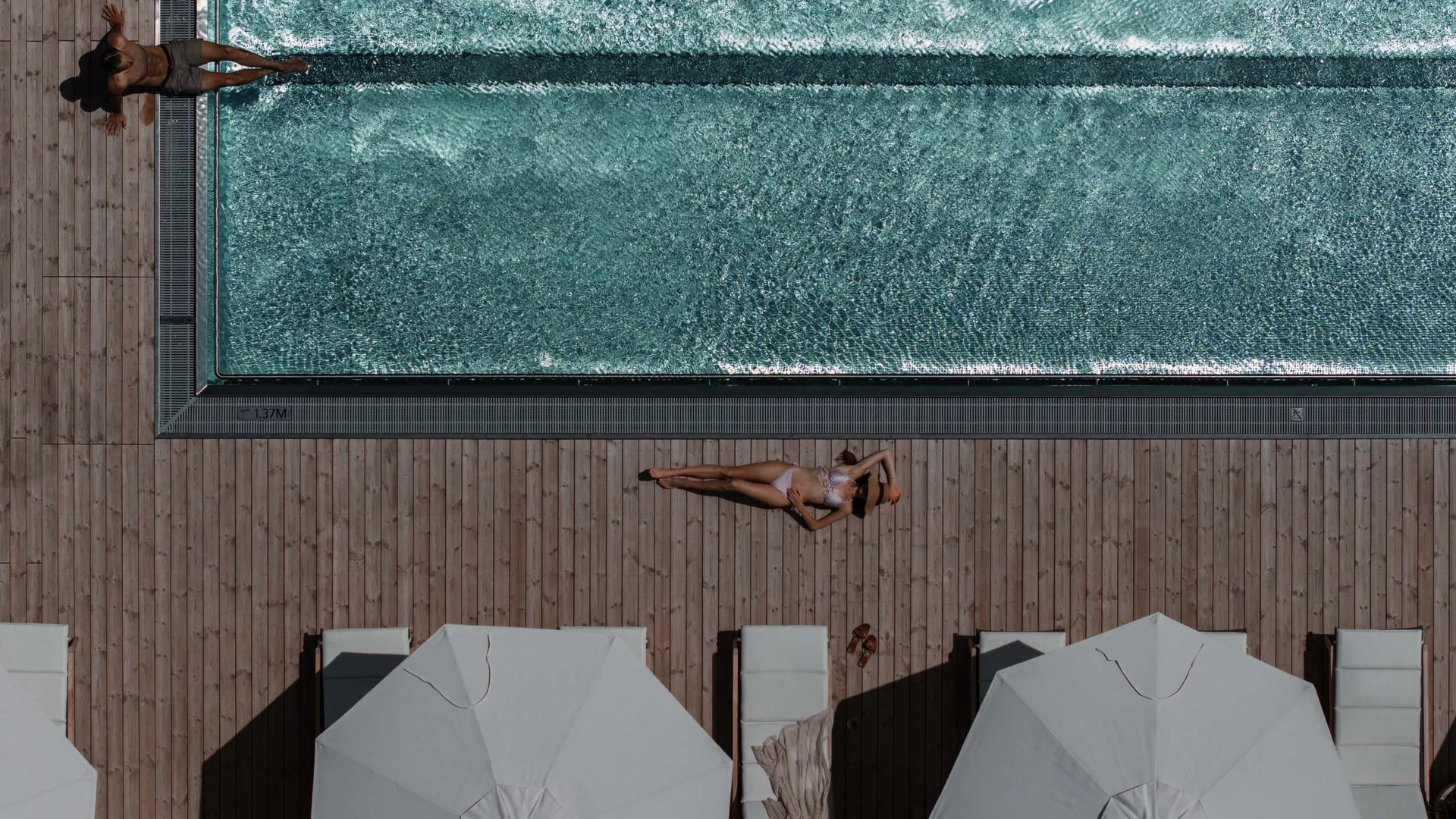 Urlaub am Neusiedler See: exklusive Angebote im NILS am See Luftaufnahme von Menschen, die an einem Pool auf Holzterrasse entspannen