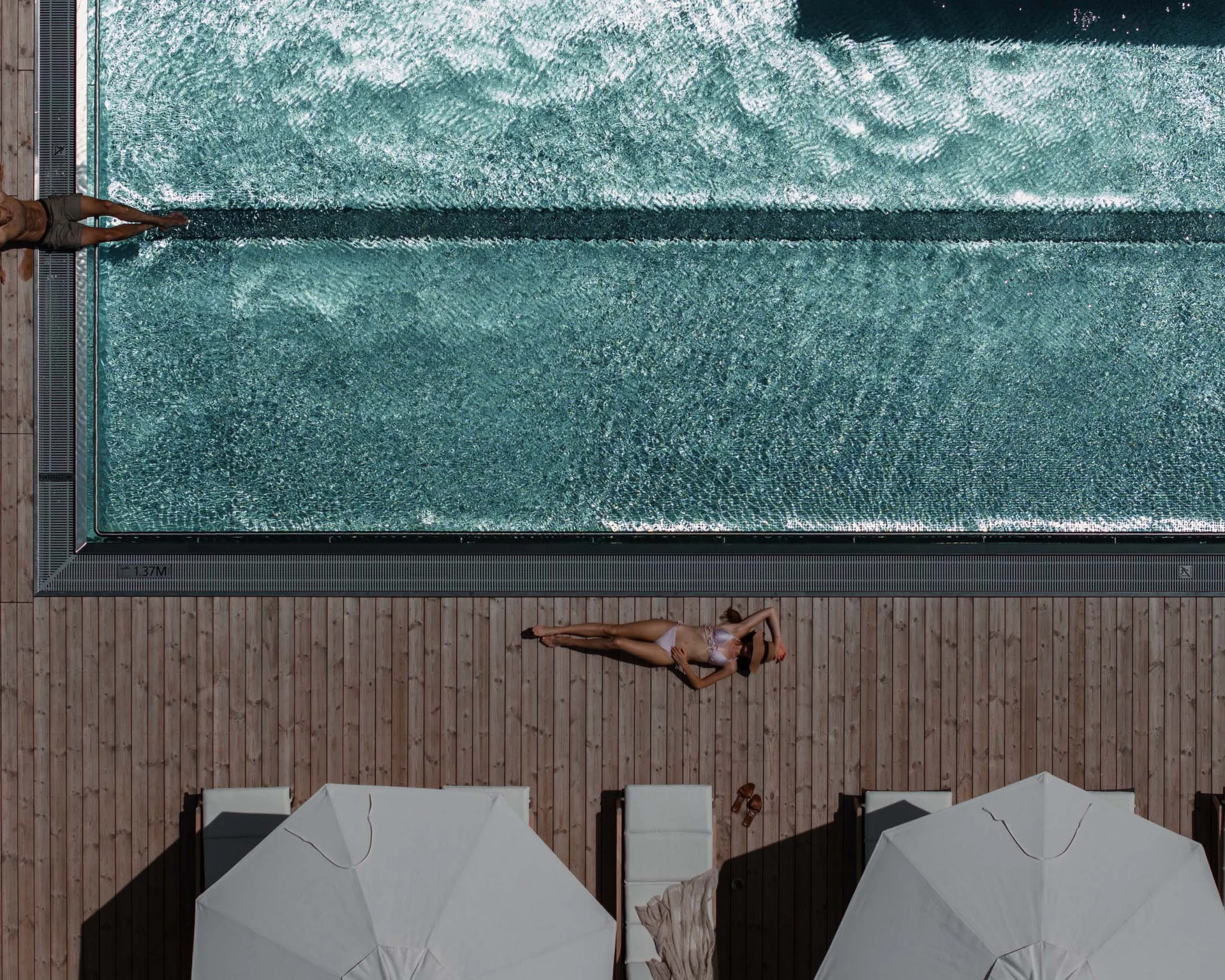 NILS am See: Impressionen eines Orts für das süße Leben Luftaufnahme von Menschen, die an einem Pool auf Holzterrasse entspannen
