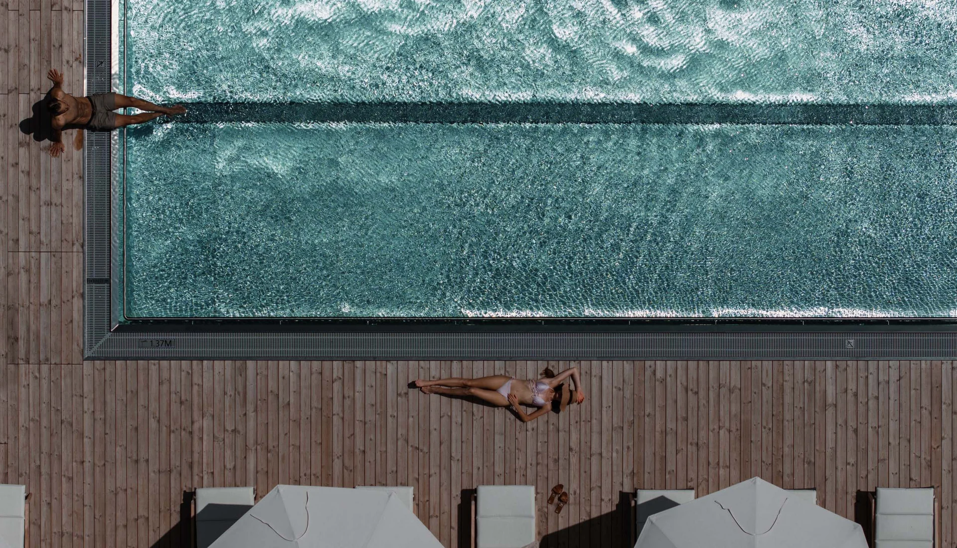 NILS am See: das Hotel am Neusiedler See mit Pool und Seebad Luftaufnahme von Menschen, die an einem Pool auf Holzterrasse entspannen
