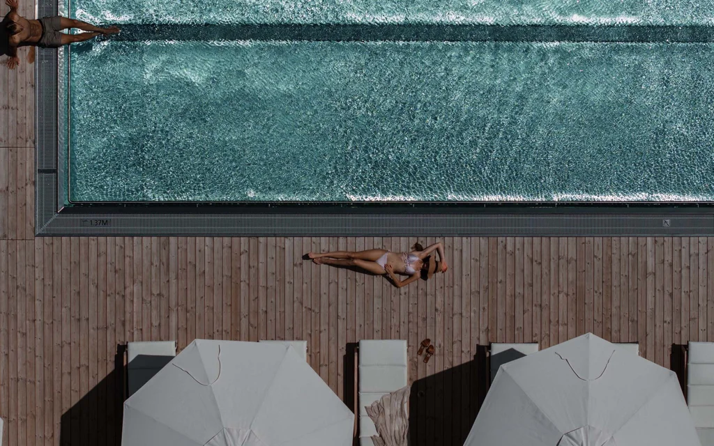 Entschleunigung in unserem Hotel in Weiden am See Luftaufnahme von Menschen, die an einem Pool auf Holzterrasse entspannen