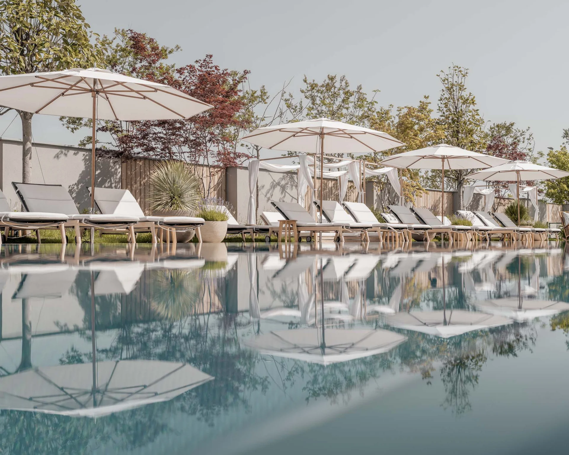 NILS am See: Impressionen eines Orts für das süße Leben Schwimmbad mit Sonnenschirmen und Liegestühlen, Bäume im Hintergrund