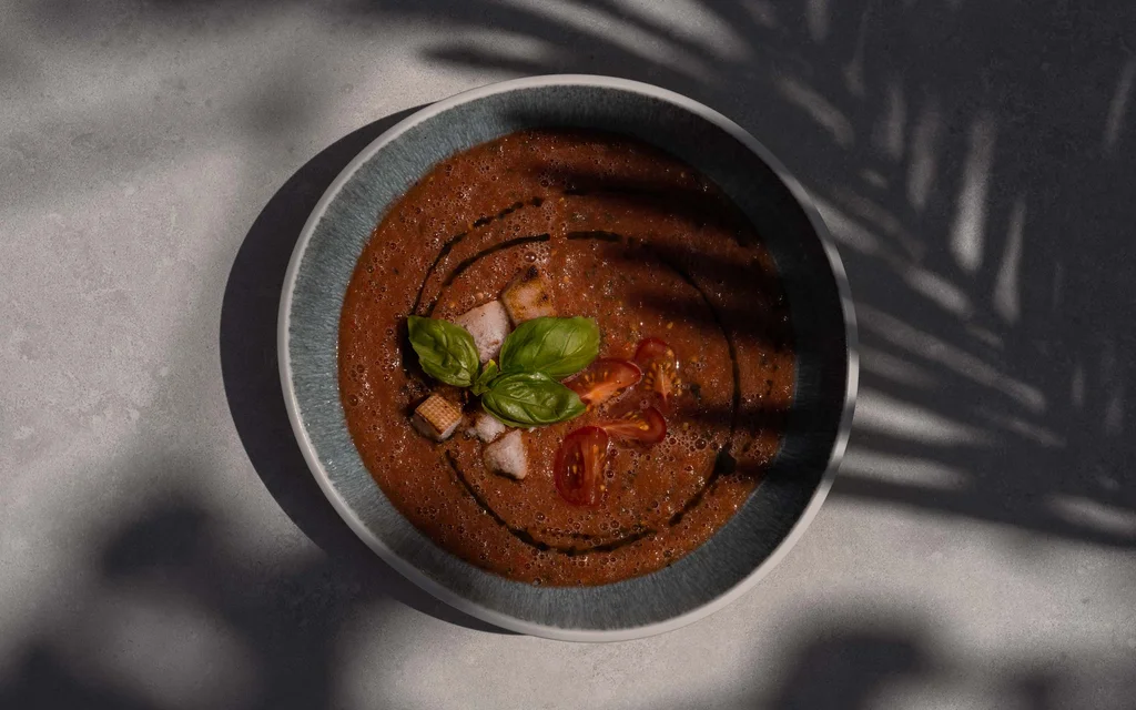 NILS am See: das Adults-only-Hotel im Burgenland Tomatensuppe mit Croutons und Basilikum in Schale, mit Schatten einer Pflanze