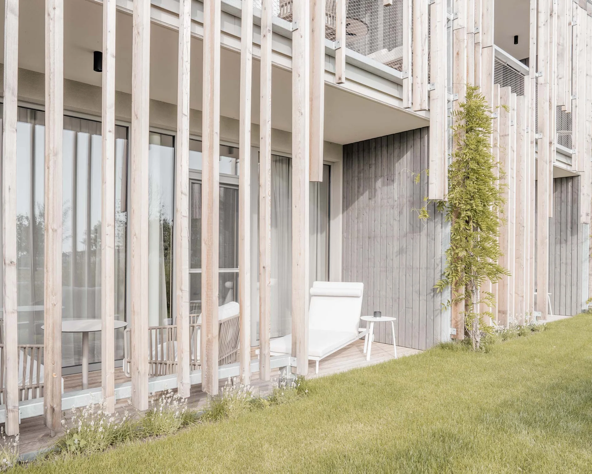 NILS am See: Impressionen eines Orts für das süße Leben Moderne Terrasse mit Liegestuhl und kleinen Tischen hinter Holzlatten