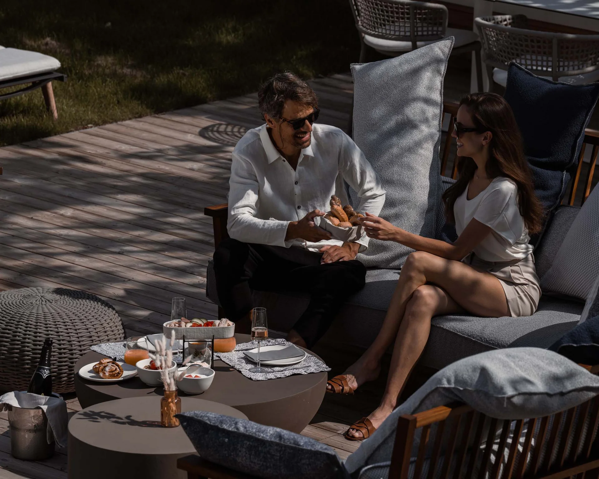 NILS am See: Impressionen eines Orts für das süße Leben Pärchen genießt Snacks und Getränke im sonnigen Garten auf moderner Terrasse