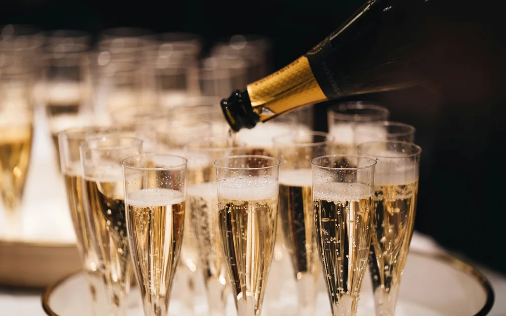 NILS am See | Silvester am Neusiedler See Champagner wird in mehrere Sektgläser eingeschenkt