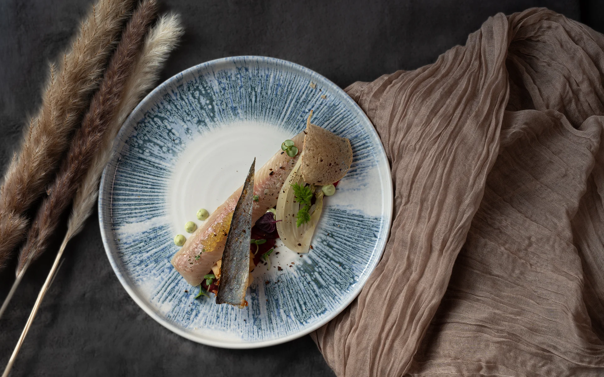 Restaurant Ankkuri am Neusiedler See Fein angerichteter Fisch mit Beilagen auf graublaue Keramikplatte