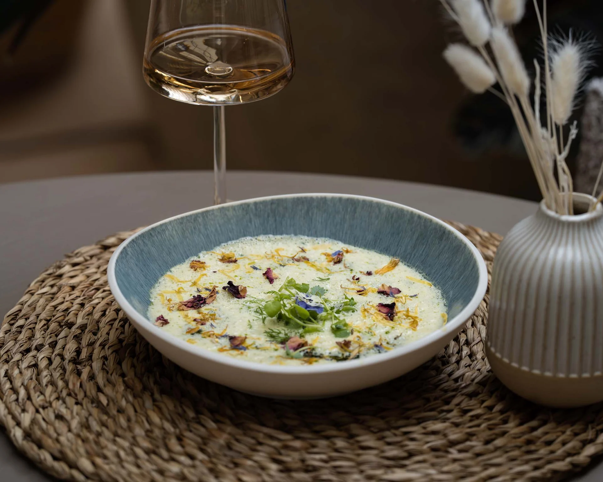 NILS am See: Impressionen eines Orts für das süße Leben Suppenschüssel mit cremiger Suppe und essbaren Blüten auf einem gewebten Platzset