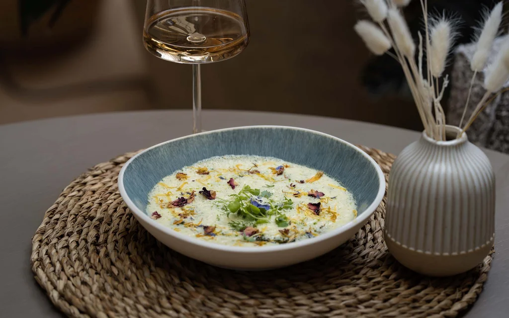 NILS am See: unser Event- und Seminarhotel im Burgenland Suppenschüssel mit cremiger Suppe und essbaren Blüten auf einem gewebten Platzset