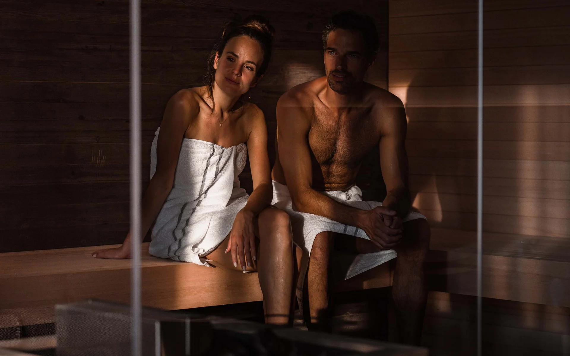 NILS am See: das Boutiquehotel am Neusiedler See Paar entspannt in Sauna, beide mit weißen Handtüchern umwickelt