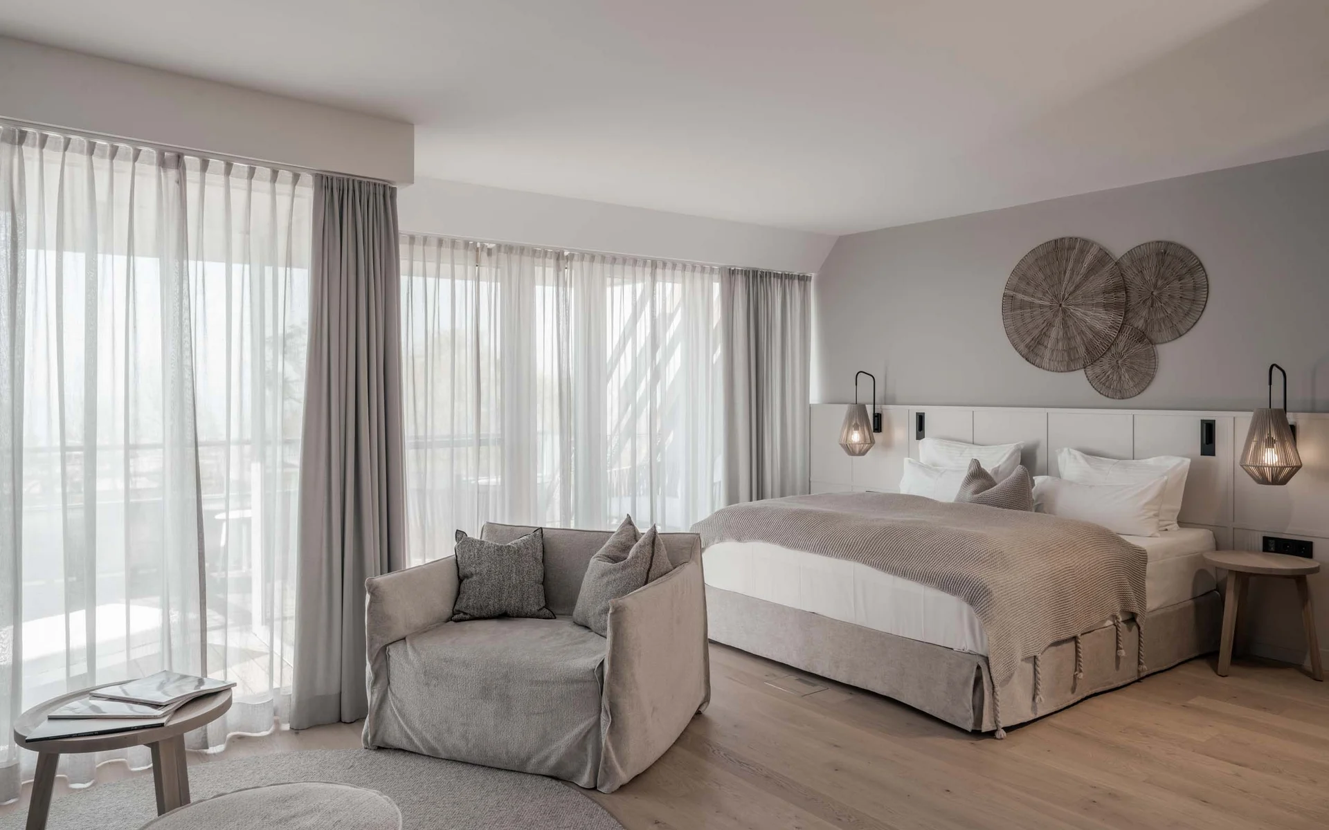 NILS am See: das Boutiquehotel am Neusiedler See Modernes Schlafzimmer mit großem Bett, Sessel, Vorhängen und Wanddekoration