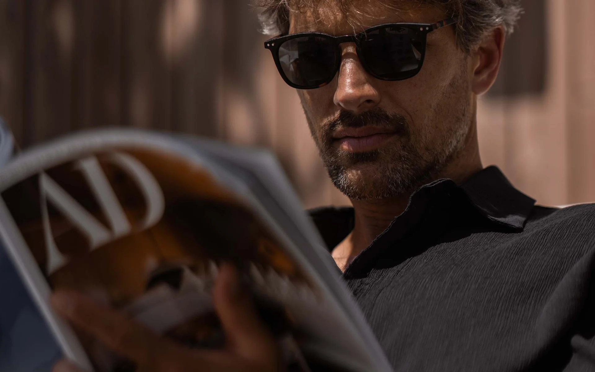 NILS am See: das Boutiquehotel am Neusiedler See Mann mit Sonnenbrille liest Magazin im Schatten