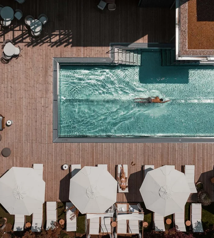 NILS am See: das Boutiquehotel am Neusiedler See Vogelperspektive eines Pools mit Schwimmer und Liegestühlen mit Sonnenschirmen