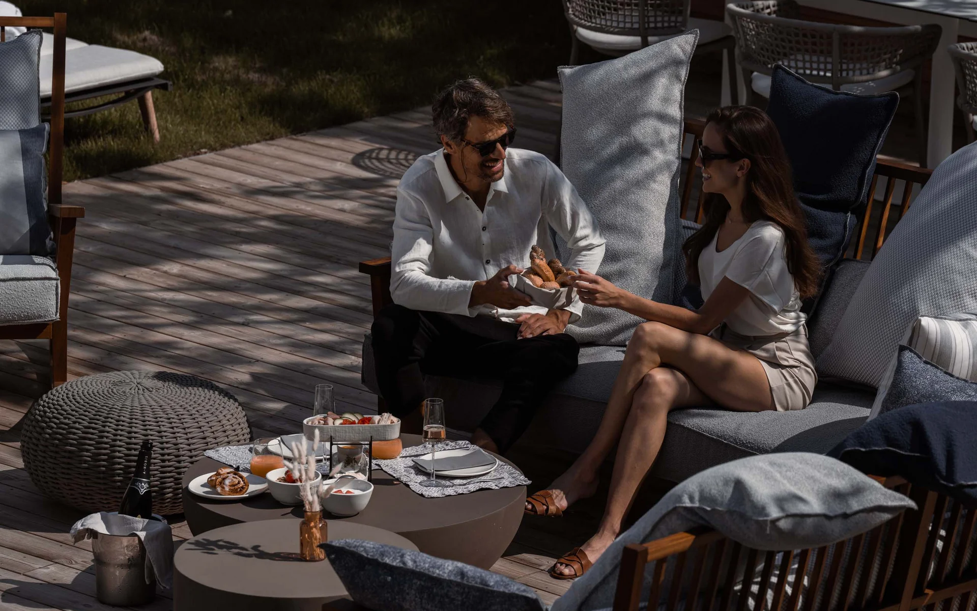 NILS am See: das Boutiquehotel am Neusiedler See Pärchen genießt Snacks und Getränke im sonnigen Garten auf moderner Terrasse
