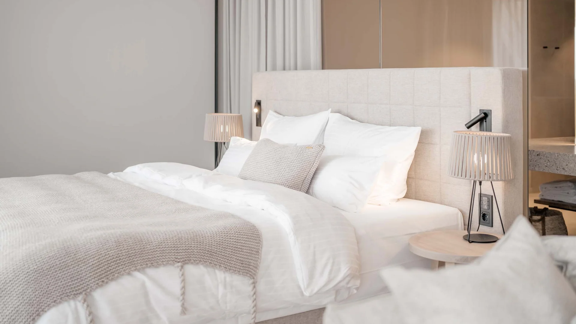 NILS am See: das Boutiquehotel am Neusiedler See Modernes Schlafzimmer mit weißem Bett, Beistelltisch und Tischlampe